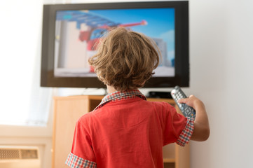 Kid watching television with remote in his hand.
