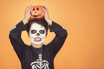 Happy Halloween.funny child in a skeleton costume with halloween pumpkin over on his head