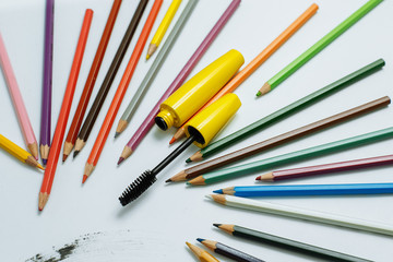 yellow mascara among pencils on a white background