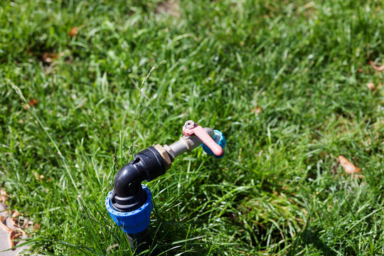Faucet in a park to adjust water hose on it to hydrate the green grass