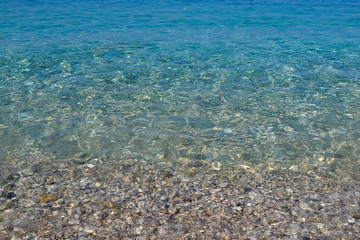 Naklejka na ściany i meble square background image of calm turquoise sea on shingle beach