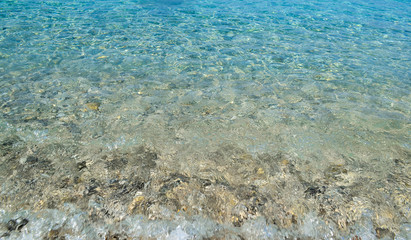 square background image of calm turquoise sea on shingle beach