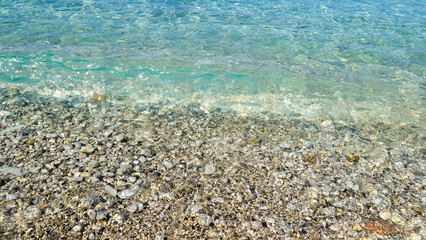 square background image of calm turquoise sea on shingle beach