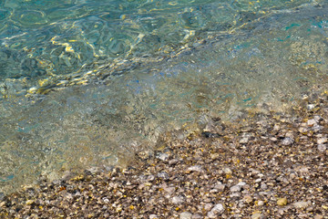 square background image of calm turquoise sea on shingle beach