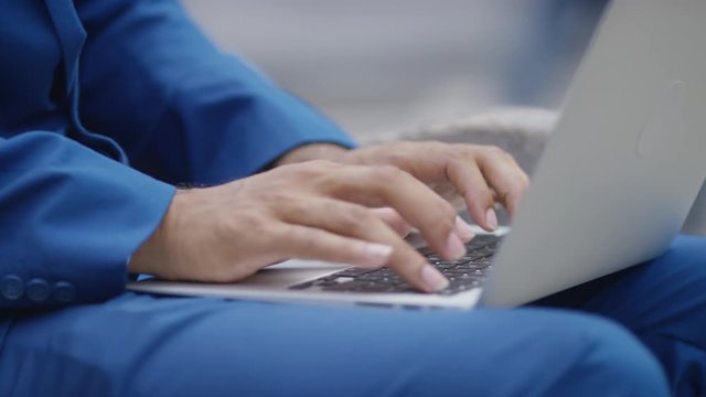 Busy city worker on his phone and laptop outdoors on a bench