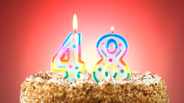 Birthday cake with a burning birthday candle. Number 48. Background changes color
