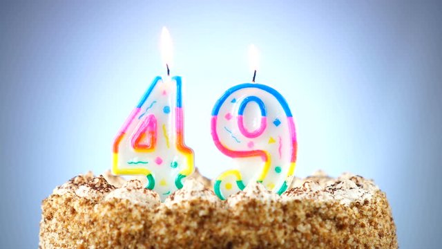 Birthday cake with a burning birthday candle. Number 49. Background changes color