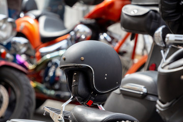 black retro helmet on a leather motorcycle seat. On a blurred background other motorbikes out of...