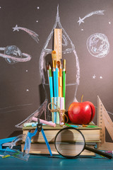 Back to school background. pencils, brushes and rulers, crayons and books lined up in the shape of a rocket. 
