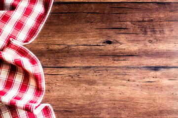 Checkered red napkin on an old wooden brown background, top view. Image with copy space. Kitchen table with a towel - top view with copy space. 
