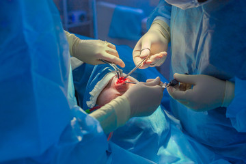 Surgeon and his assistant performing cosmetic surgery on nose in hospital operating room. Nose...