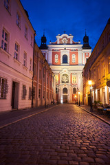 Fototapeta na wymiar The cobbled street and the facade of the baroque church at night in Poznan.
