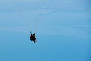 Paraglider flying over the Garda Lake (Lago di Garda or Lago Benaco), Panorama of the gorgeous Garda lake surrounded by mountains. Paragliding is very popular sport in Monte Baldo. Malcesine, Italy