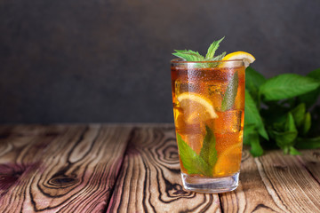Glass of iced tea with mint and lemon. Cold drink. Rustic style