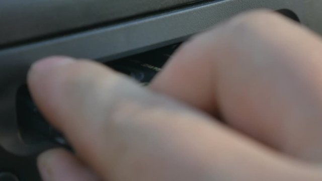 Man inserting the cassette into the old car cassette player.