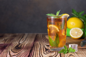 Glass of iced tea with mint and lemon. Cold drink. Rustic style