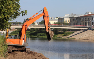 Construction site with heavy construction equipment on the river bank in the city