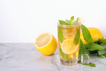 Glass of iced tea with mint and lemon on marble table. Cold drink.