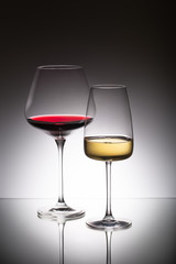 Glasses of red and white wine on mirror surface
