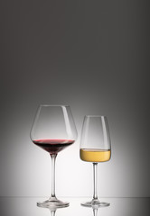 Glasses of red and white wine on mirror surface