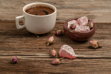 coffee and turkish delight on a wooden table decorated with dried roses