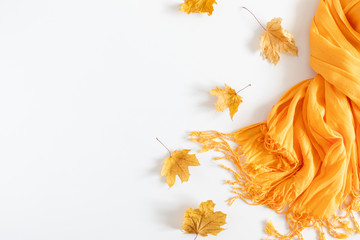 Autumn cozy composition. Dried autumn leaves, yellow scarf on white background. Fall relax concept. Flat lay, top view, copy space