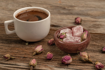 coffee and turkish delight on a wooden table decorated with dried roses