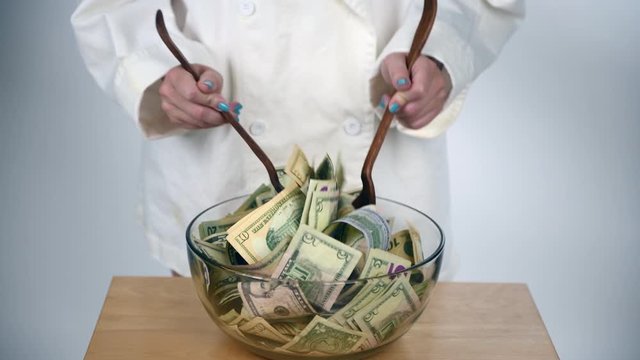 Female Chef with tongs stirring and mixing green bills