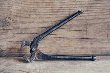 Old rusty pincers on a wooden background. A tool for gripping and pulling things