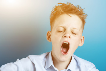 the boy in the t-shirt is tired, wants to sleep and yawns