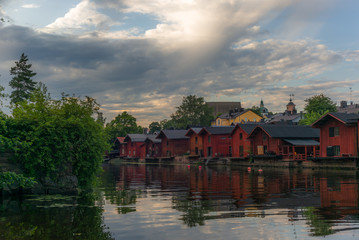 Obraz premium The colorful red wooden warehouses of Porvoo in Finland reflecting in the river at sunset during a warm summer evening - 4