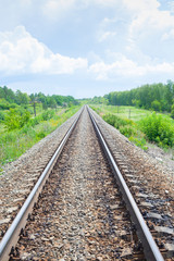 A railway through the summer green fields.  Beautiful green railway tree landscape sky. Beautiful landscape and railway. Railway transport. Vertical