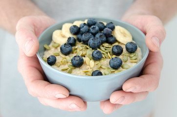 Blue bowl of fresh blueberries in mans hands