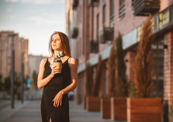 Young beautiful girl with coffee in the street. Sunset