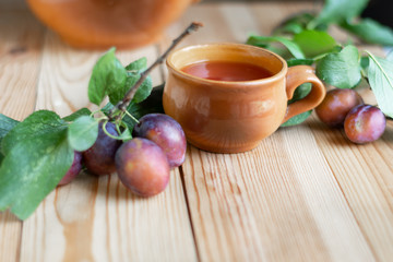 Sweet red plums with leaves on the wooden rustic table, selective focus