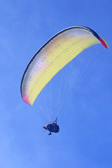 Yellow tanderm paraglider in a blue sky