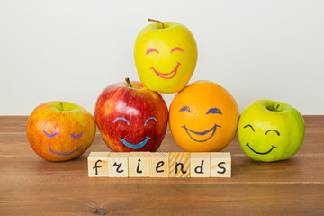Different apples and orange with funny faces, tolerance, originality or friendship concept.