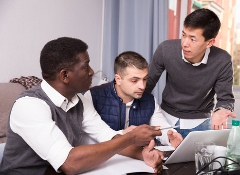 Three seriouse men are working with project on laptop together