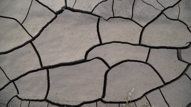 Panning over deep cracks in the mud as it dries out from the heat.