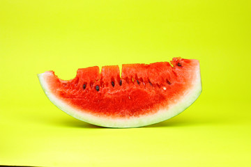Eaten watermelon slice on yellow background.  Summer time fruit.