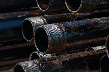 View of drilling pipes casing and tubing stacked at open yard of oil and gas warehouse.