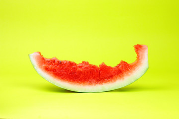 Eaten watermelon slice on yellow background.  Summer time fruit.