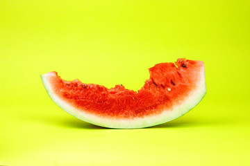Eaten watermelon slice on yellow background.  Summer time fruit.