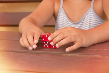 A girl's hands playing with four red dice