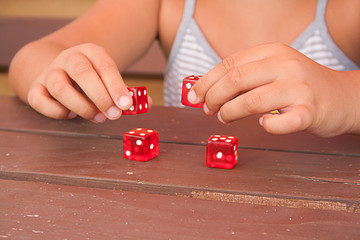 A girl's hands playing with four red dice