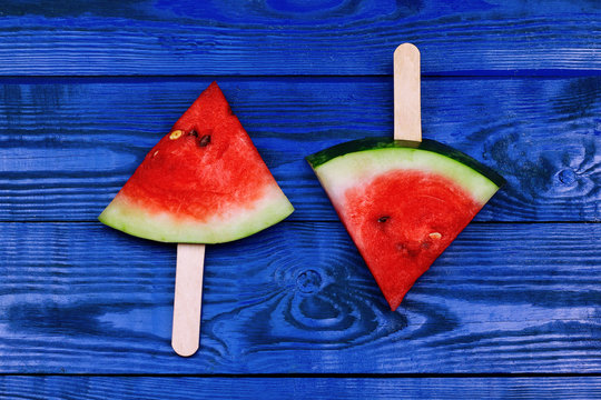 Watermelon slice popsicles with ice cream stick on blue wooden background. summer fruit background.