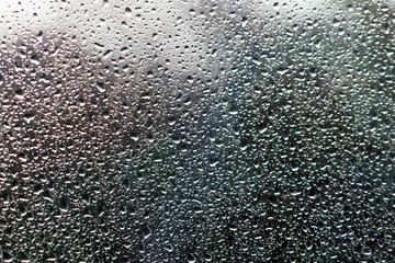 drops on glass against the background of trees and sky at sunset.
