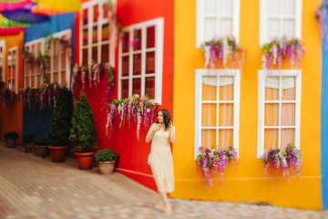 A girl in yellow dress walks the streets with bright decoration of the city. Tilt-shift lens blur