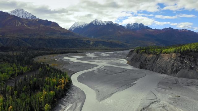 Aerial Forward: Sandy, Tree Filled Valley, Snow Peaked Mountains In Distance - Chugach National Forest, Alaska