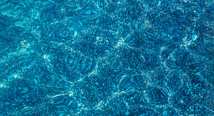Background of sea water. Texture seabed through a clean, blue water. Blue water background.